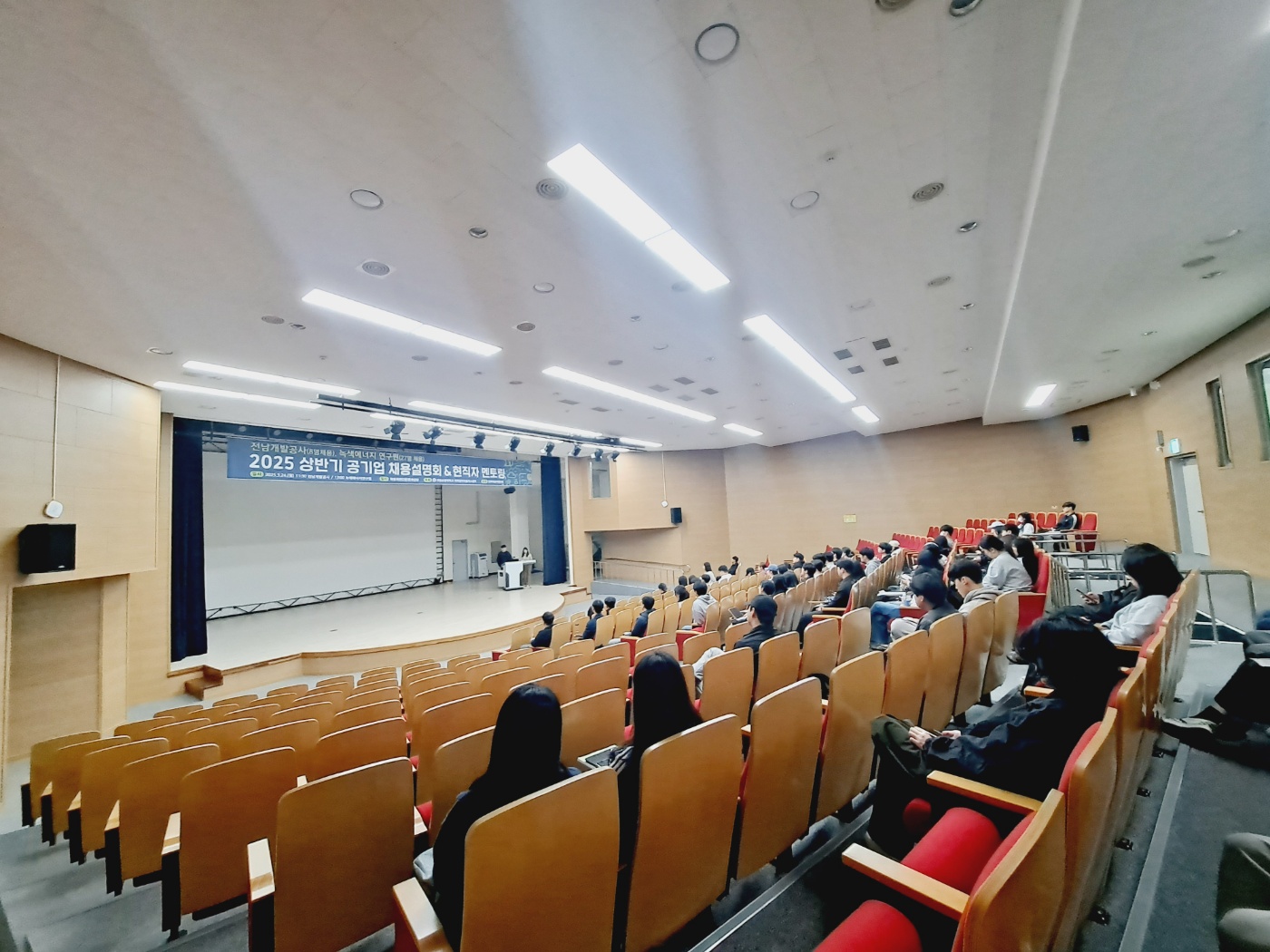 학생들이 강당에 앉아 동문 현직자의 멘토링을 듣고 있는 사진